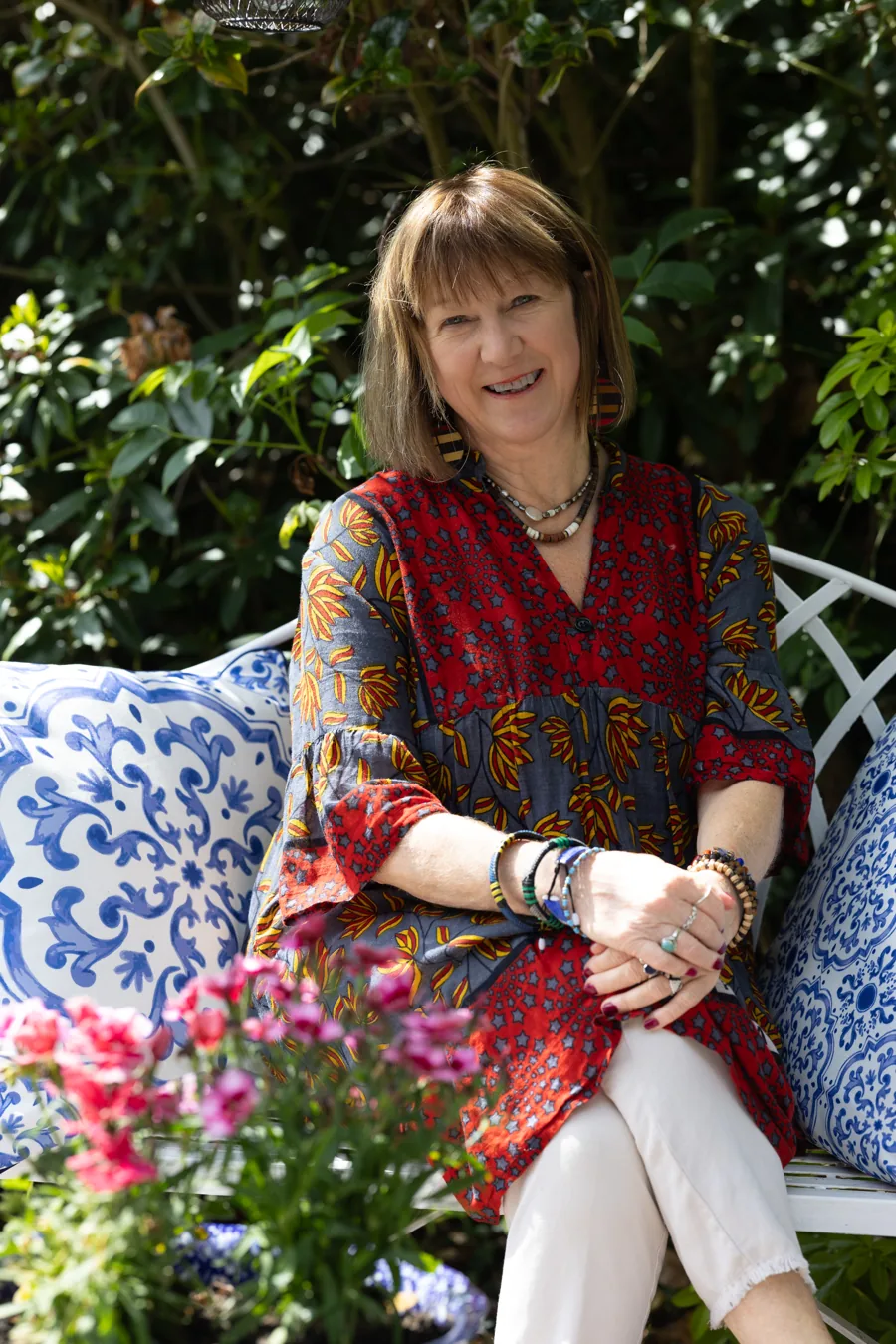 Dr Alison Dow, seated outdoors, wearing a printed dress